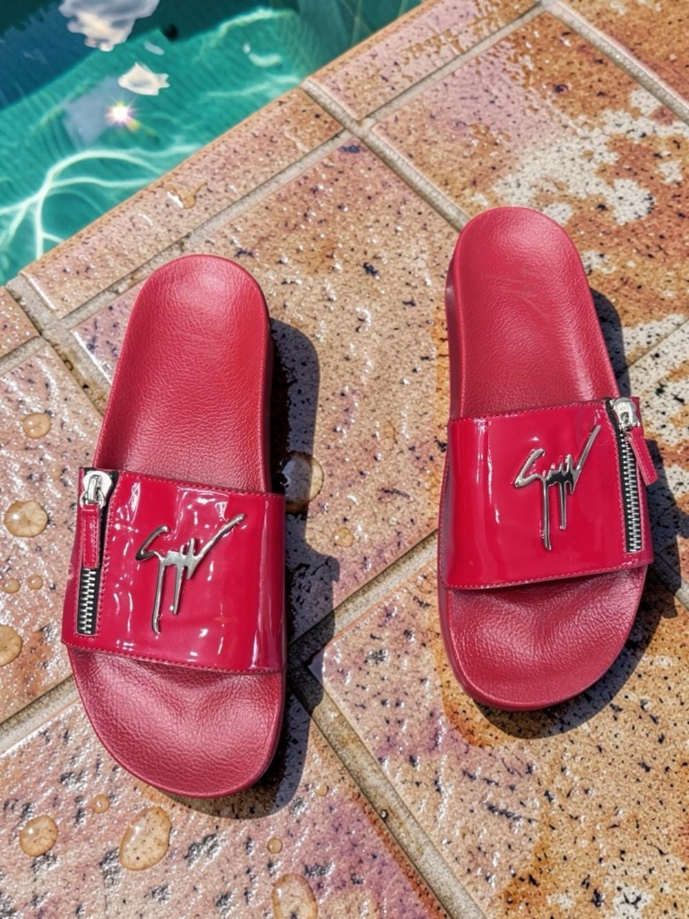 Red slides with zippers on a textured surface near a pool.